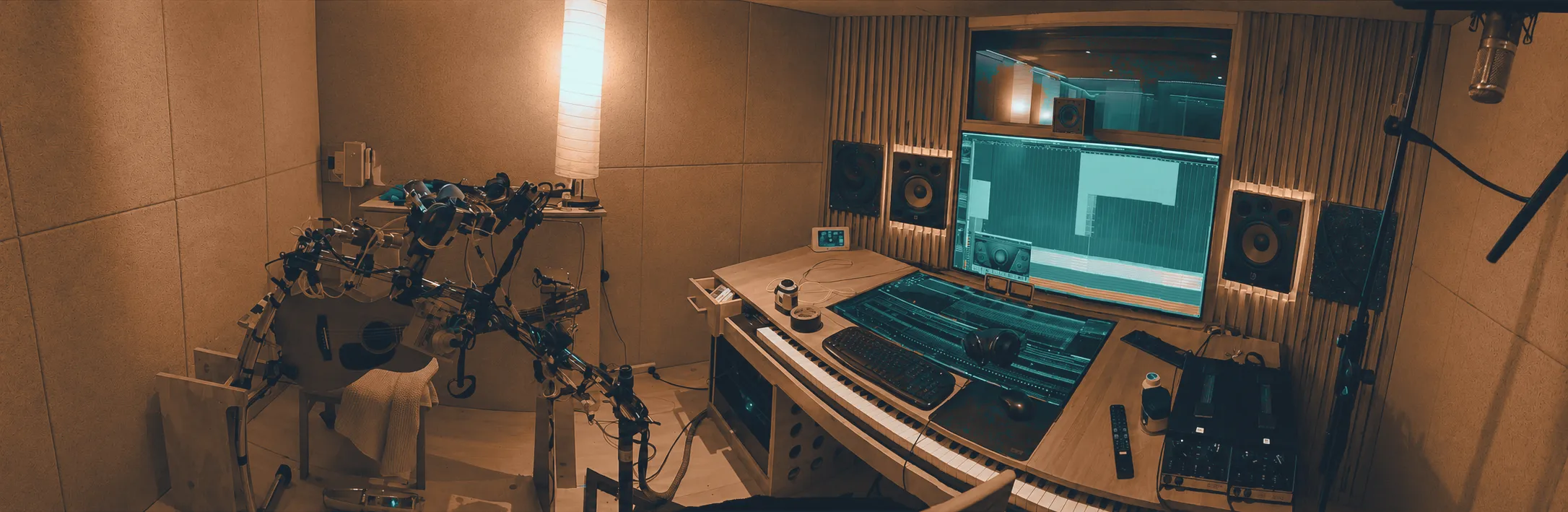 A finished control room: acoustic panelling and slatted diffusers around the walls, monitors and a session screen at the listening position.